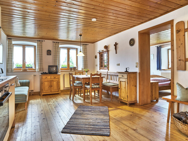 Gemütlicher Essbereich mit Möbeln aus Holz und angrenzender moderner Küche in der Ferienwohnung des Familienhofs.